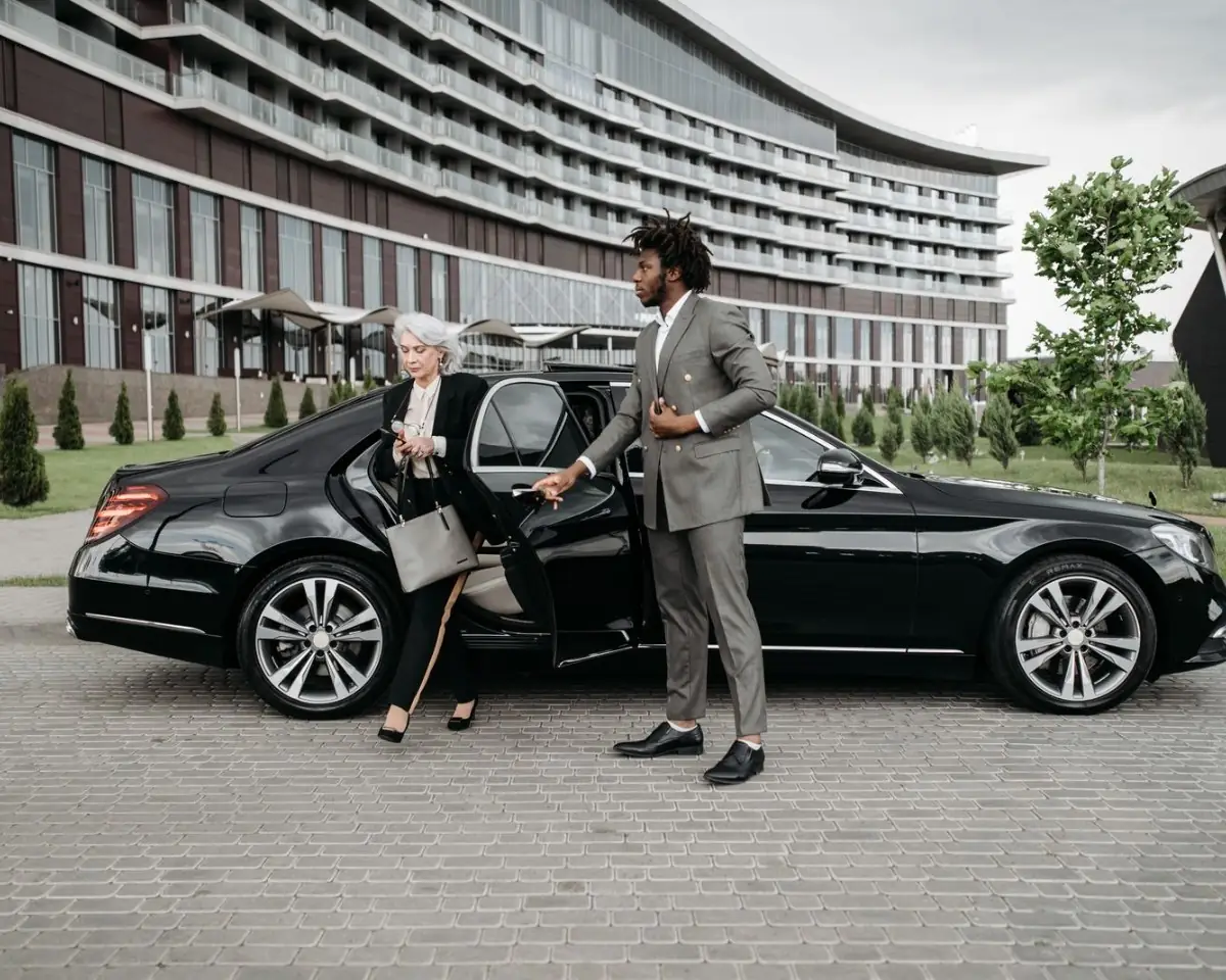 Chauffeur holding the door of a black Mercedes-Benz S-Class for an executive